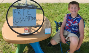 Boy sets up compliment stand to brighten passersby's day