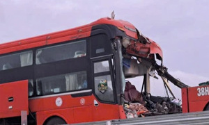 Passenger bus crashes into container truck on expressway, trapping driver