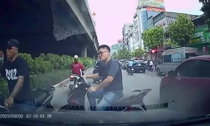 Two motorcyclists weave through traffic against the flow on busy Hanoi street