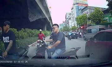 Two motorcyclists weave through traffic against the flow on busy Hanoi street