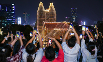 Visitors flock to check in at Notre Dame Cathedral as lights illuminate