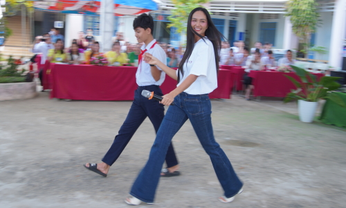 H'Hen Nie catwalks with student at schoolyard