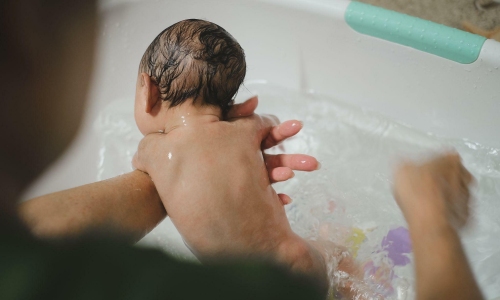 Should newborns be bathed multiple times during hot weather?