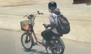 Male student rides electric bicycle hands-free on national highway