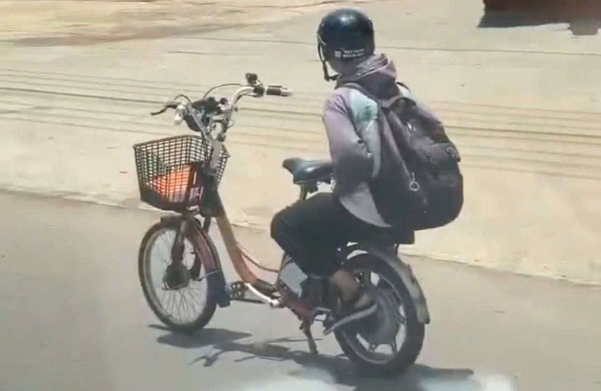 Male student rides electric bicycle hands-free on national highway