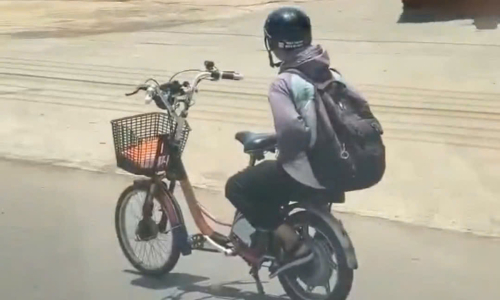 Male student rides electric bicycle hands-free on national highway