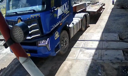 Tractor-trailer trapped between railway barrier as train approaches