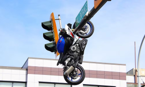 Motorcycle airborne, lands on traffic light pole after collision