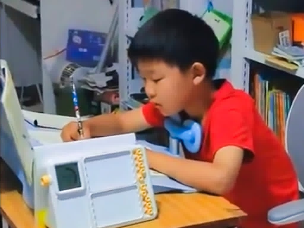 Boy pedals sewing machine while doing homework