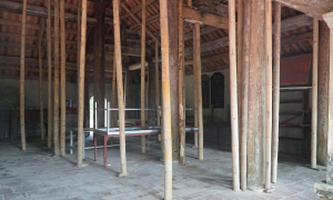 Bamboo poles prop up ancient communal house facing collapse