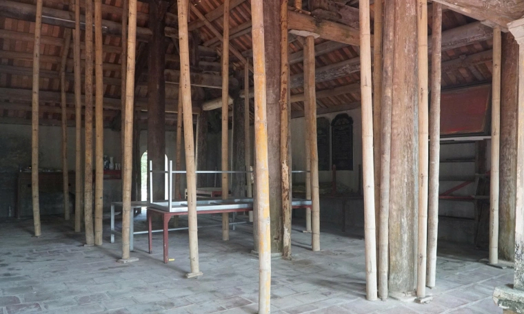 Bamboo poles prop up ancient communal house facing collapse
