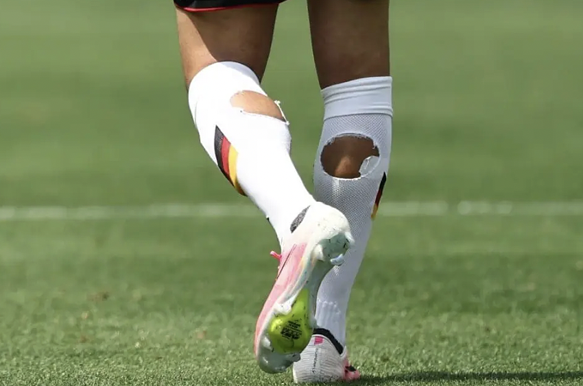 Why do many footballers wear torn socks on the field?